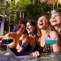 3 women enjoying drinks at the indoor pool surrounded by tropical plants