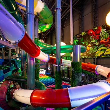 Kolorowa strefa z wielopoziomowymi zjeżdżalniami i tropikalną dekoracją